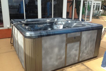 Old hot tub ready for disposal with a Stand Up Guys Junk Removal dumpster rental.